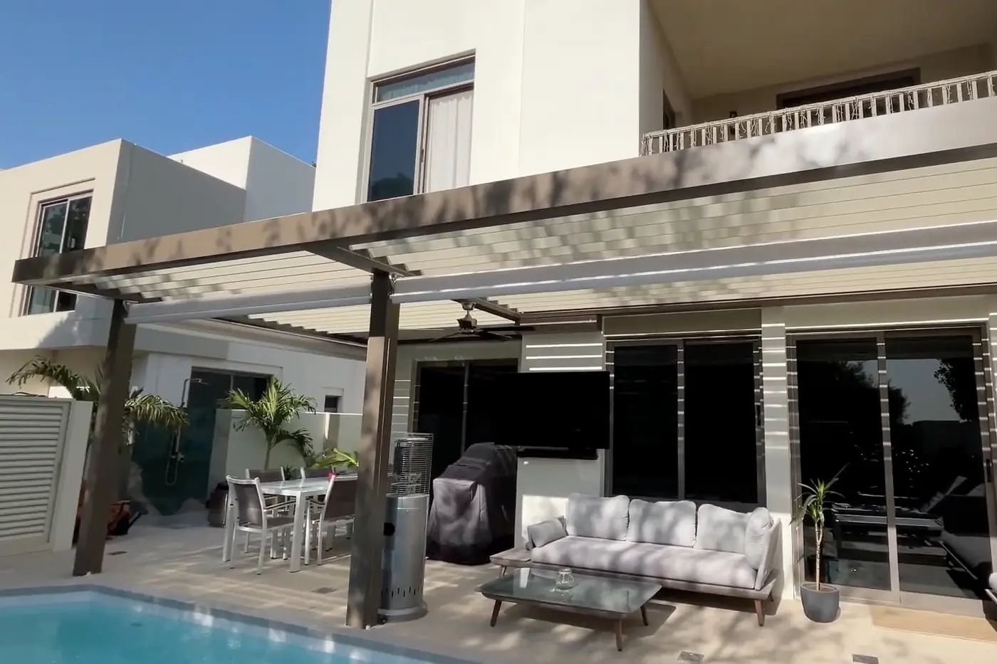 Sierra bioclimatic pergola with a cantilevered section over a pool terrace at a villa in Town Square, Dubai